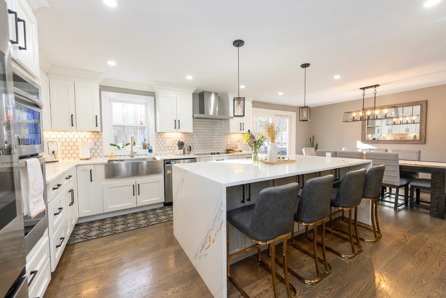 Updated kitchen with white cabinetry, gold stools, and stylish geometric backsplash.
