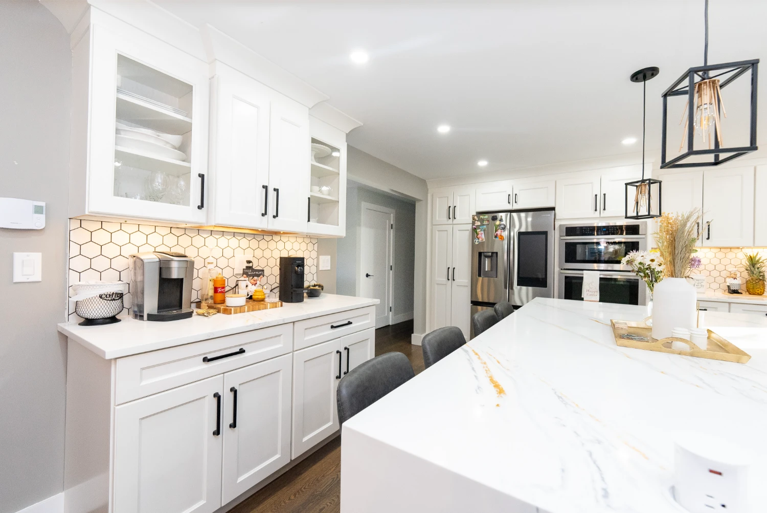 Bright kitchen renovation featuring a large island, wooden floors, and black accents.