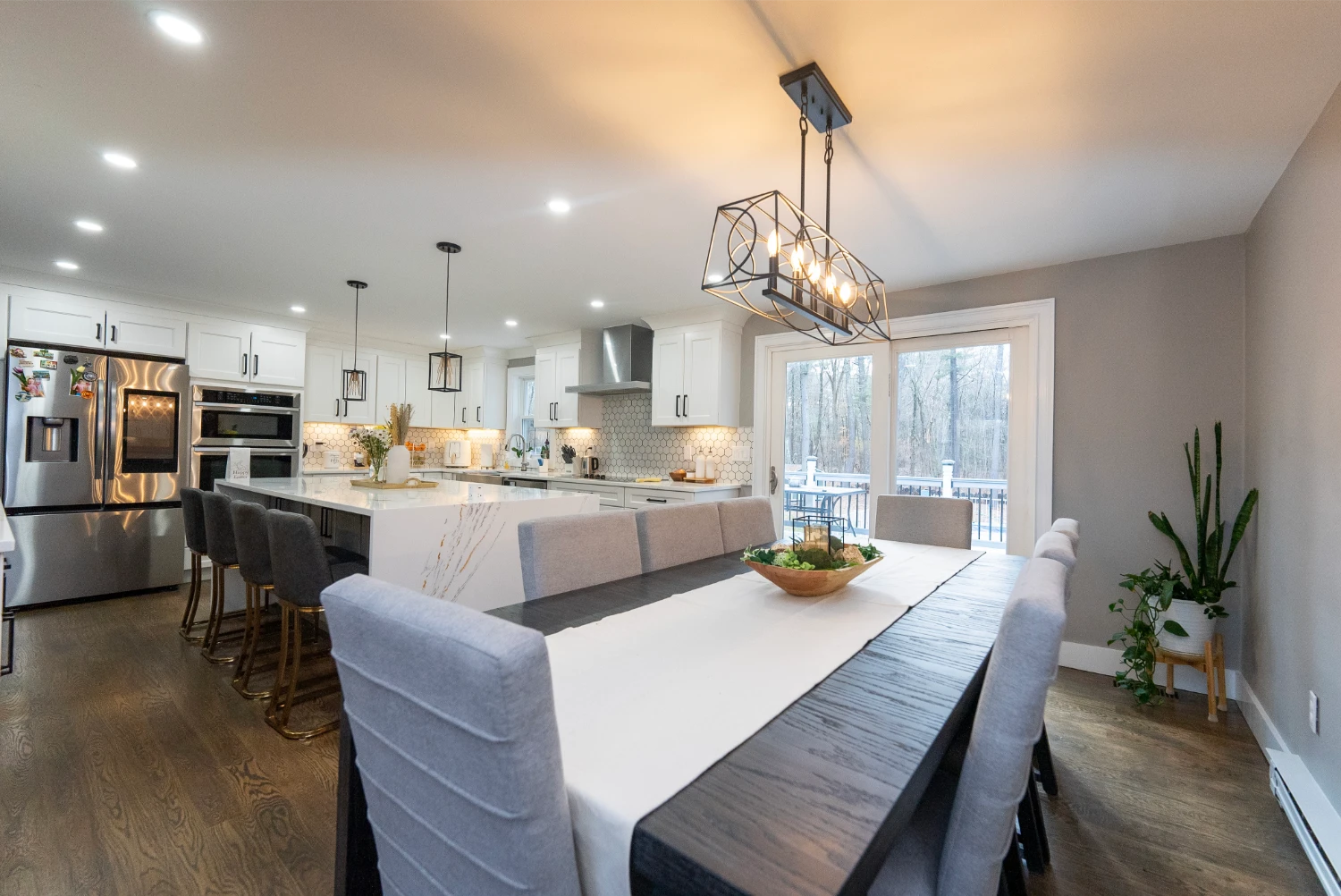 Renovated kitchen with white marble island, open shelves, and pendant lights.