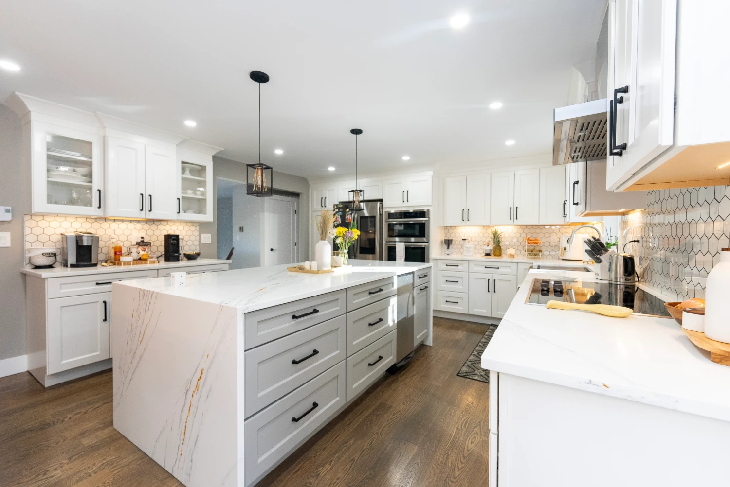 Modern kitchen remodel with white cabinets, island, and hexagon tile backsplash.